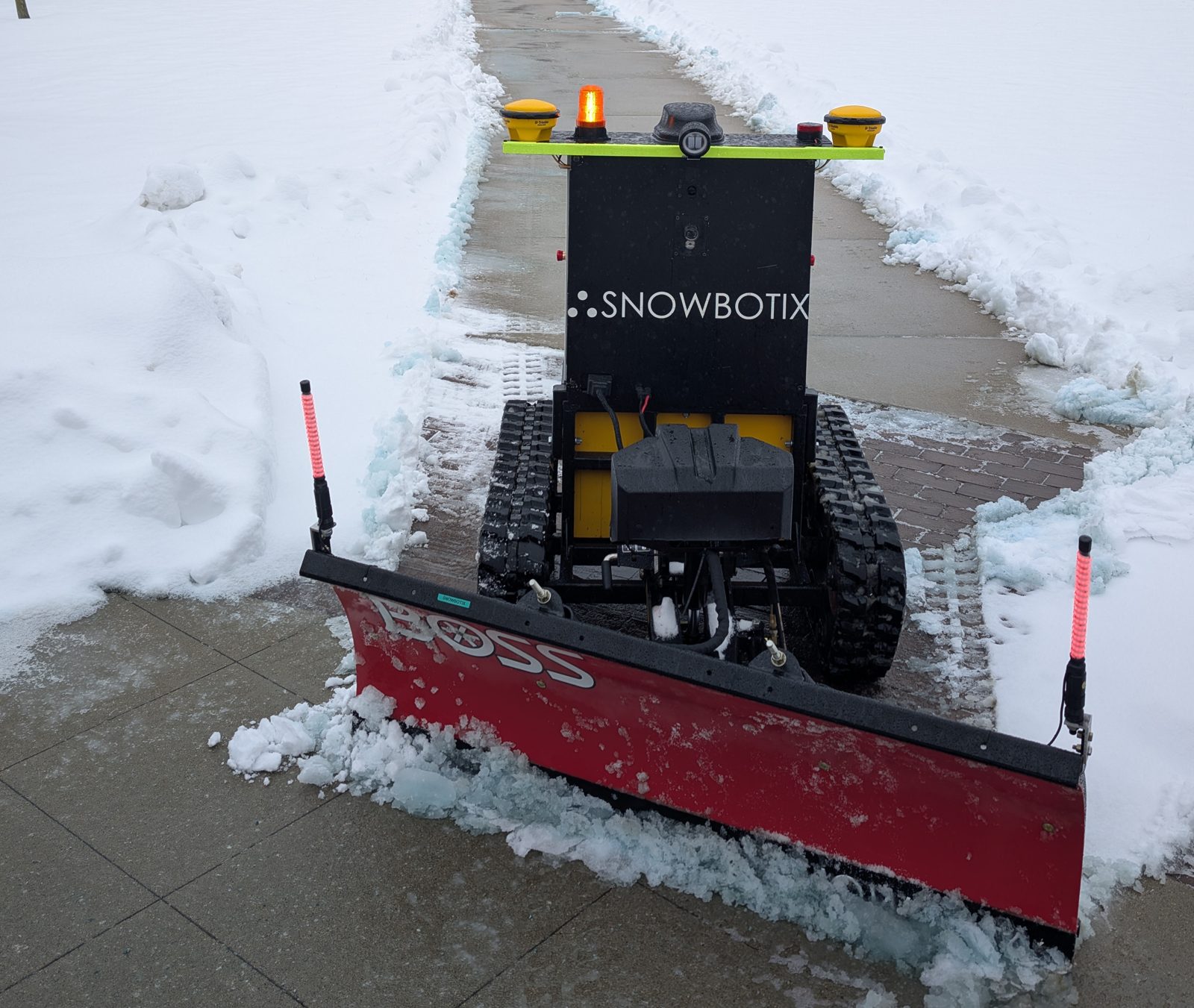 A Snowbotix all-electric autonomous robot clearing snow in a wintry outdoor setting
